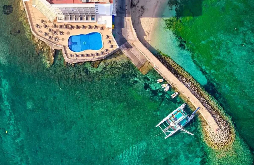 Hotel-Marqués-Es-Trenc Vista aérea del Hotel Marqués, en la costa de Mallorca, con su piscina junto a una cala de agua turquesa